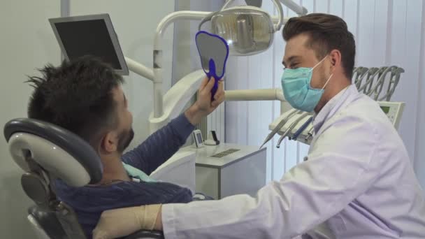 Pacjent wygląda w lustrze w biurze Dentyści - Materiał filmowy, wideo