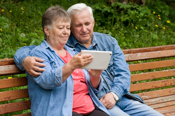 A couple of retired people use a tablet to find information on t - Photo, Image
