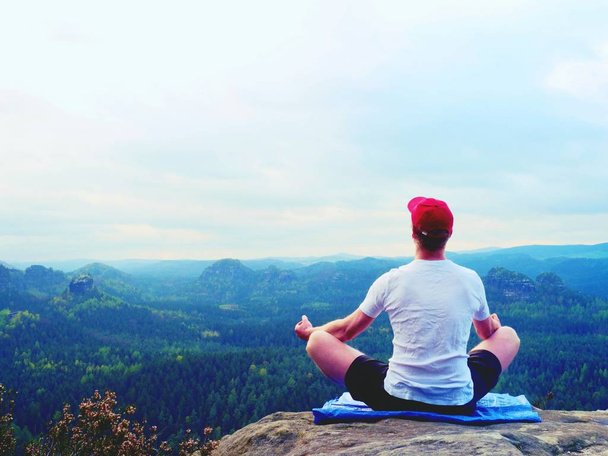 Yoga practicing  at mountain summit with aerial view of the mountain valley. Tall sportsman practicing yoga - Photo, Image