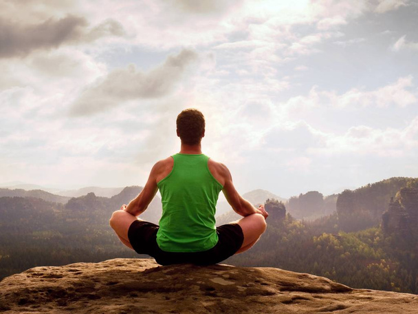 Homem meditando em Lotus Pose em penhasco rochoso. Esportista praticando Yoga na borda de pedra
  - Foto, Imagem