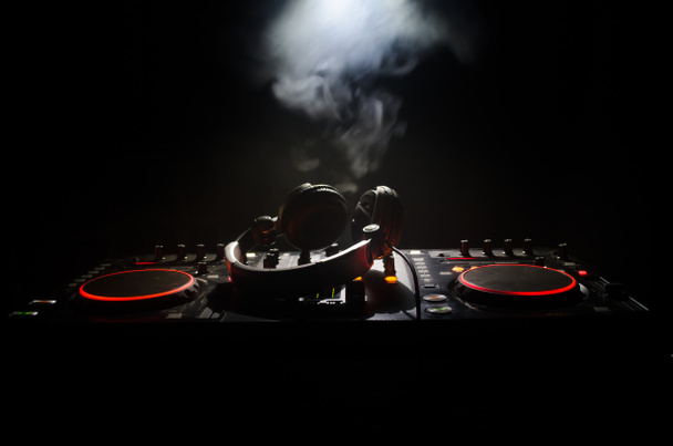 DJ κλώση, ανάμειξη και ξύσιμο σε ένα νυχτερινό κλαμπ, τα χέρια του dj τσίμπημα διάφορα στοιχεία ελέγχου γραμμής στο κατάστρωμα του dj, φώτα strobe και την ομίχλη, επιλεκτική εστίαση - Φωτογραφία, εικόνα
