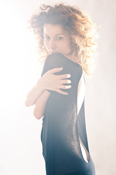 Portrait of beautiful curly girl with black dress with back light - 写真・画像