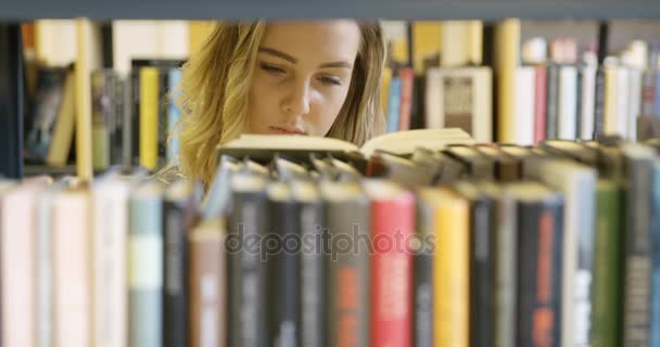 Nuori naisopiskelija etsii kirjaa koulun kirjastosta
 - Materiaali, video