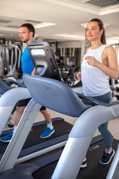Young man and woman biking in the gym, exercising legs doing car - Foto, Imagem