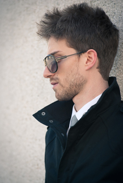 Young elegant man portrait with sunglasses against a wall - Fotó, kép
