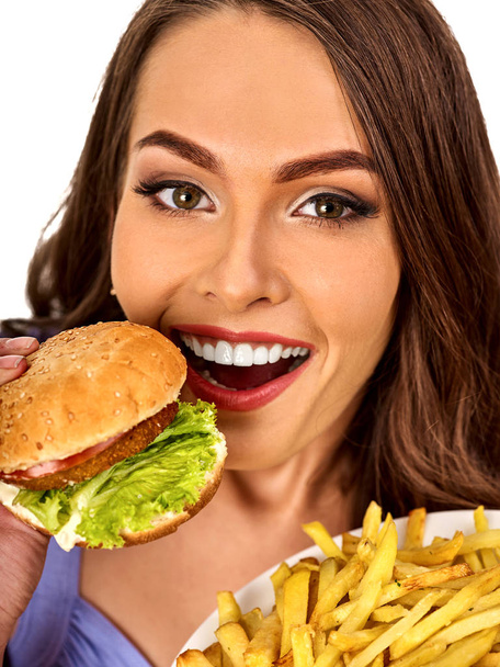 Woman eating french fries and hamburger on table. - Photo, Image