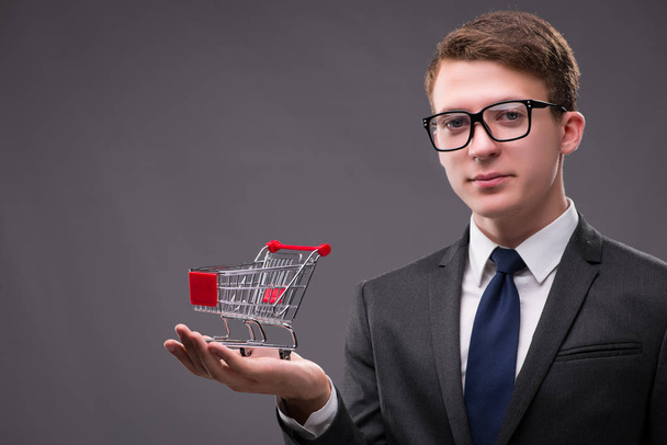 Businessman with shopping cart on gray background - Φωτογραφία, εικόνα