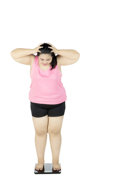 Frustrated fat woman stands on scale - Foto, imagen