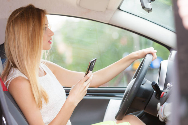 Woman using phone while driving her car - Foto, imagen