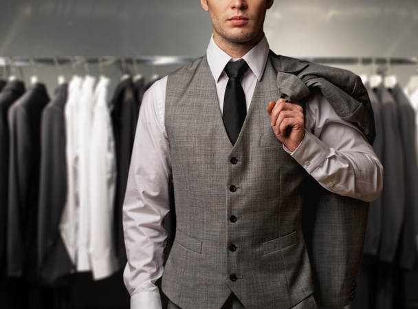 Businessman in classic vest against row of suits in shop - Photo, Image