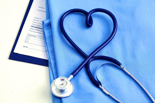 Stéthoscope médical tordu en forme de coeur allongé sur la liste des antécédents médicaux du patient et médecin bleu uniforme gros plan
 - Photo, image