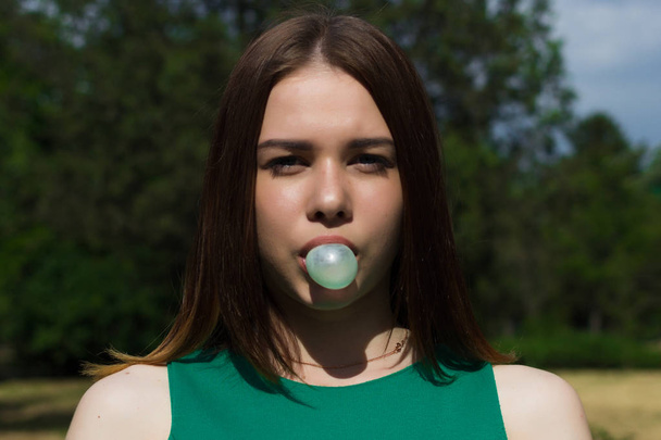 Young pretty girl chews a gum, outdoor - Фото, изображение