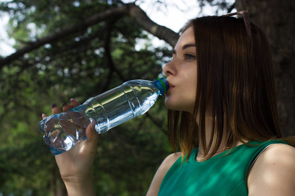 Молодая красивая девушка пьет пресную воду, на открытом воздухе
 - Фото, изображение