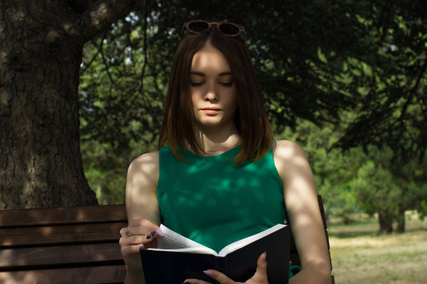 Joven chica bonita lee un libro, al aire libre
 - Foto, imagen