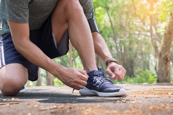 Обрізаний знімок молодого чоловіка бігуна, що затягує взуттєві шнурки
,  - Фото, зображення