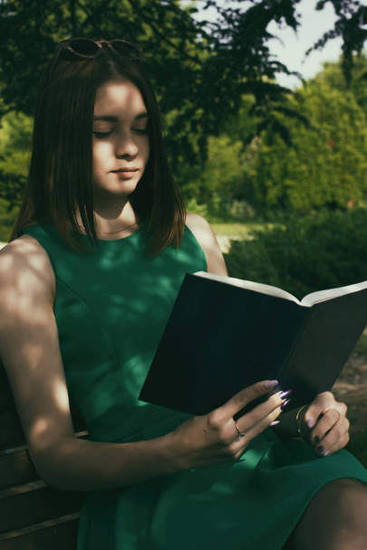 Joven chica bonita lee un libro, al aire libre
 - Foto, Imagen