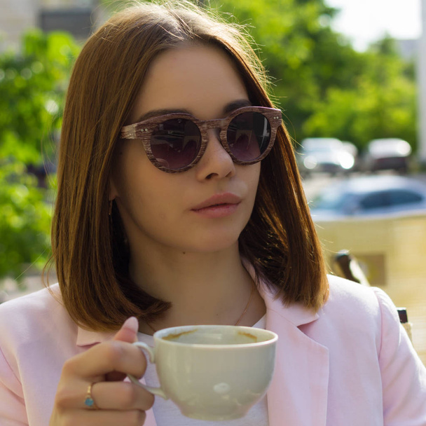 Young pretty girl drinks a cup of hot beverage, outdoor - Fotó, kép