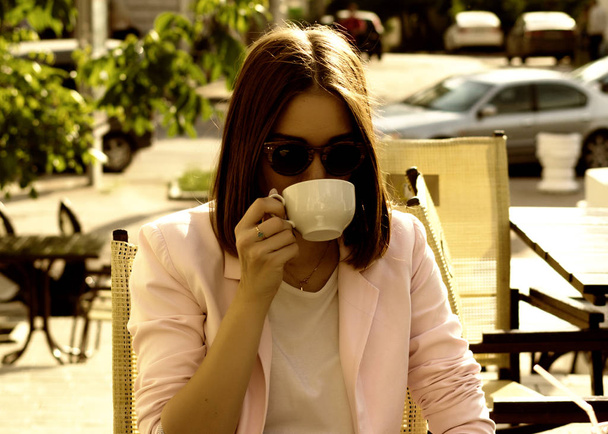 Joven chica bonita bebe una taza de bebida caliente, al aire libre
 - Foto, Imagen