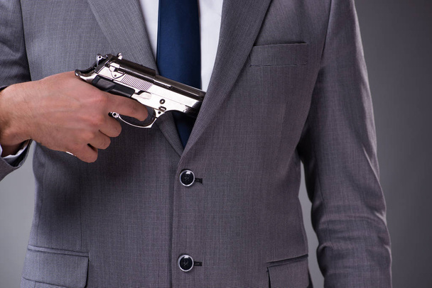 Επιχειρηματίας, τραβώντας το όπλο από την τσέπη - Φωτογραφία, εικόνα