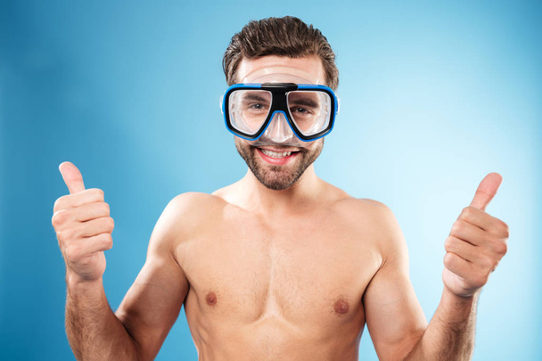 Heureux gars souriant dans les lunettes de natation montrant pouces geste
 - Photo, image
