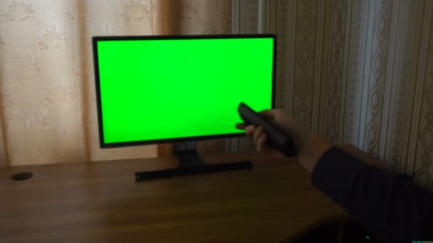 Mão masculina com canais de comutação remota de TV em um ponto de vista de TV de tela verde
 - Filmagem, Vídeo