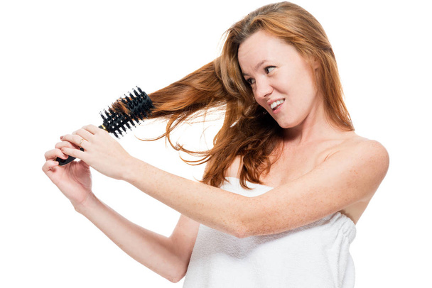 Woman combing tangled red hair after shower on white background - Photo, image