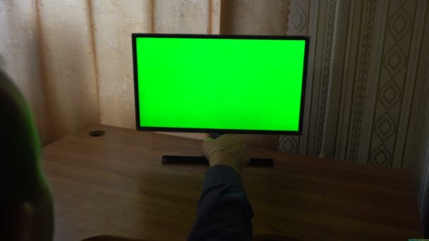 Mannenhand met Tv afstandsbediening schakelen kanalen op een groen scherm Tv oogpunt - Video