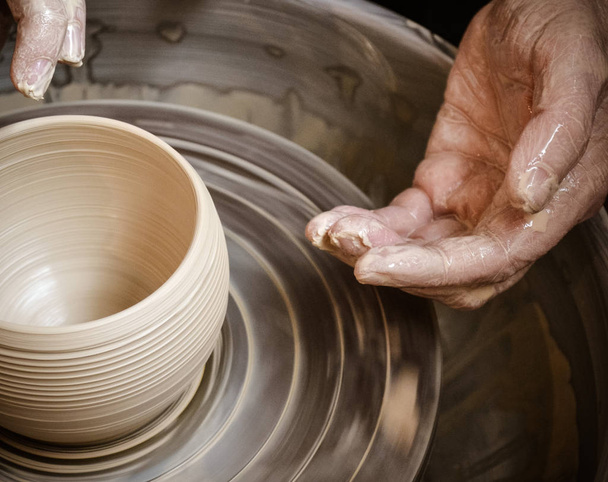 Handen van de meester potter en vaas van klei op de pottenbakkers-wiel - Foto, afbeelding