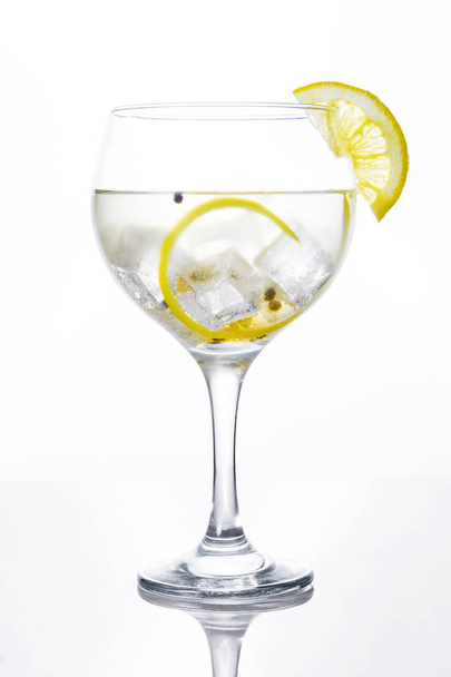 白い背景の上のレモンのジントニックのグラス - 写真・画像