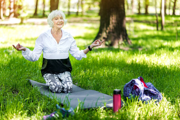 Iloinen vanha nainen tekee rentoutumista harjoituksia metsässä
 - Valokuva, kuva