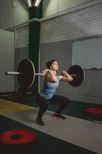 Strong woman lifting barbell as a part of crossfit exercise routine - Fotó, kép