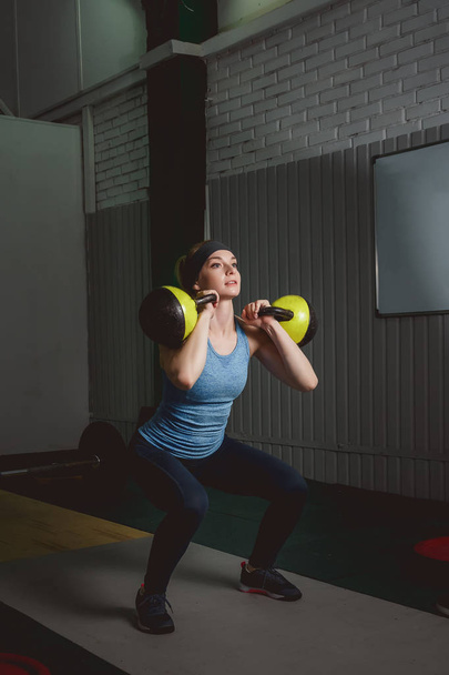 Fitness woman training by kettlebell. Fit young lady doing crossfit exercise. - 写真・画像