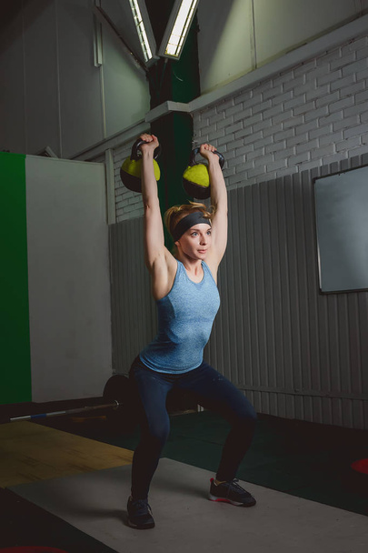 Fitness woman training by kettlebell. Fit young lady doing crossfit exercise. - Foto, afbeelding