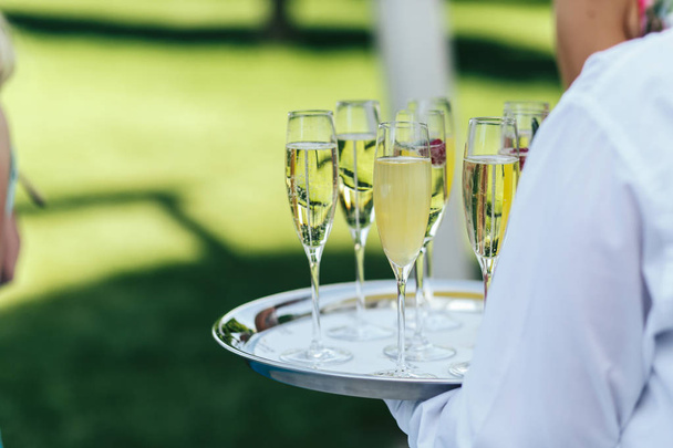 Waiter in white chirt holds a tray with champagne flutes - 写真・画像