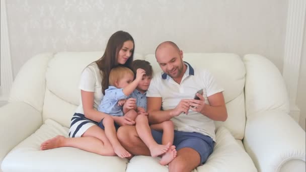 Padres felices y sus hijos pequeños mirando fotos por teléfono
 - Imágenes, Vídeo