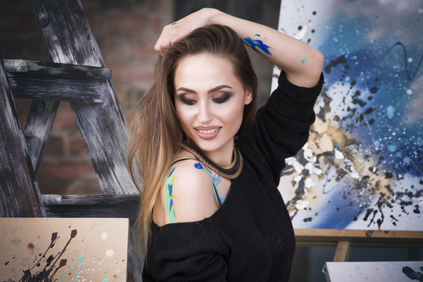 Young female artist painting abstract picture in studio, beautiful sexy woman portrait - Фото, зображення