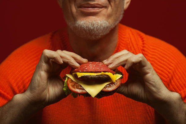 Unhealthy eating. Junk food concept. Portrait of fashionable mature man eating burger - Foto, Imagen