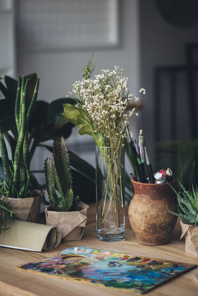 grüne Pflanzen mit Kunstgegenständen auf dem Tisch - Foto, Bild