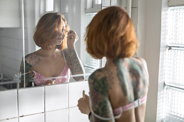 Tattooed girl does makeup - Фото, изображение