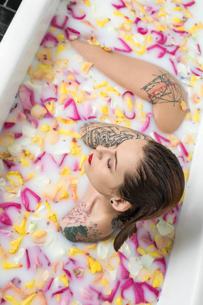 Delightful girl with wet hair and colorful tattoos sits in the w - Fotoğraf, Görsel