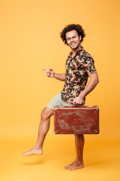 Attractive young african man holding suitcase - 写真・画像