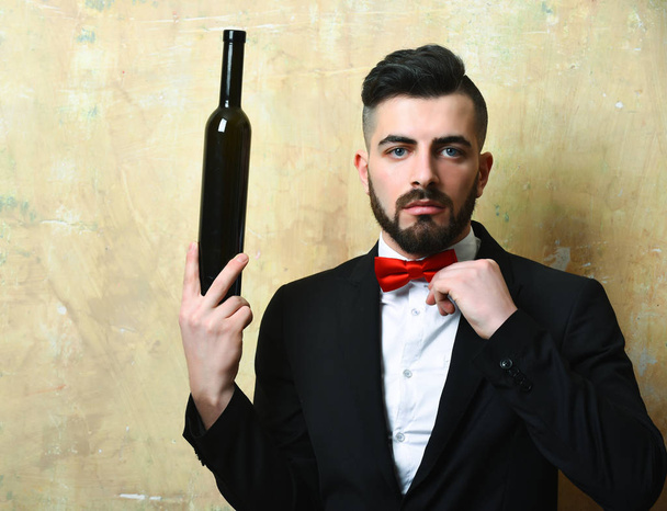Bearded white collar worker holds bottle of alcoholic drink - Fotó, kép