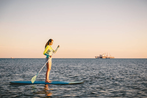 Chica de pie paddle boarding
  - Foto, Imagen