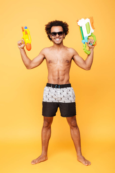 Cheerful young african man holding toy water gun. - Photo, Image