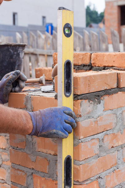 Construction maçon travailleur mesurant avec niveau professionnel les briques sur les murs
. - Photo, image