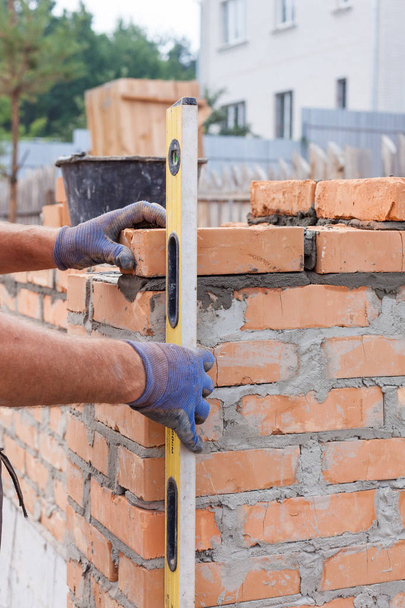 Працівник будівельного цегли з професійним рівнем цегли на стінах
 - Фото, зображення