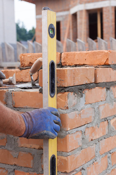Trabalhador pedreiro construção medindo com nível profissional os tijolos nas paredes
 - Foto, Imagem