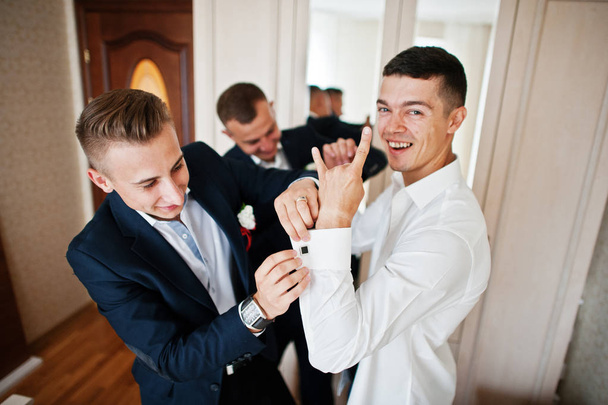 Groomsmen helping groom to dress up and get ready for his weddin - Фото, зображення
