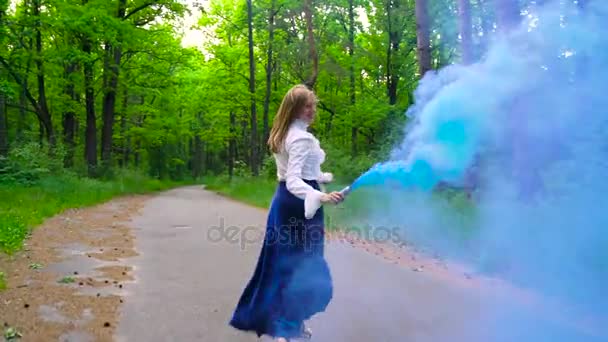 Žena v krásných šatech prochází v lese mává barevné kouře, zpomalené - Záběry, video