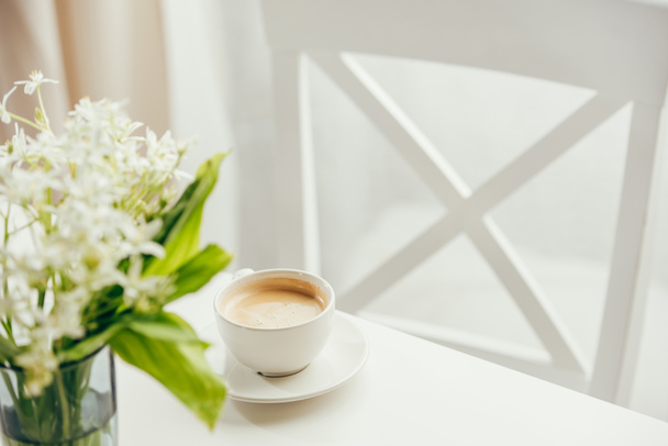 cup of coffee with bouquet of flowers on tabletop - Foto, Imagen